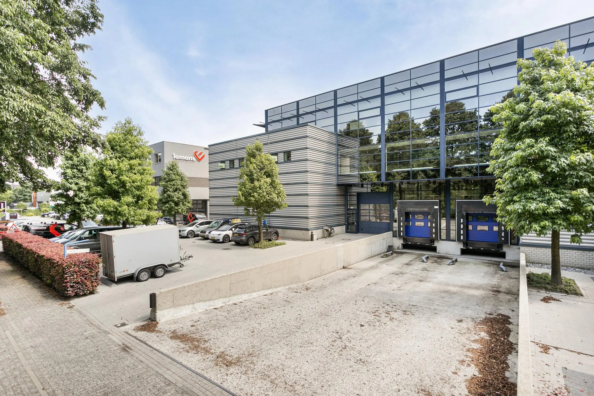 Moderne bedrijfsloods met laadperrons en parkeerplaatsen bij het pand van Lomans.
