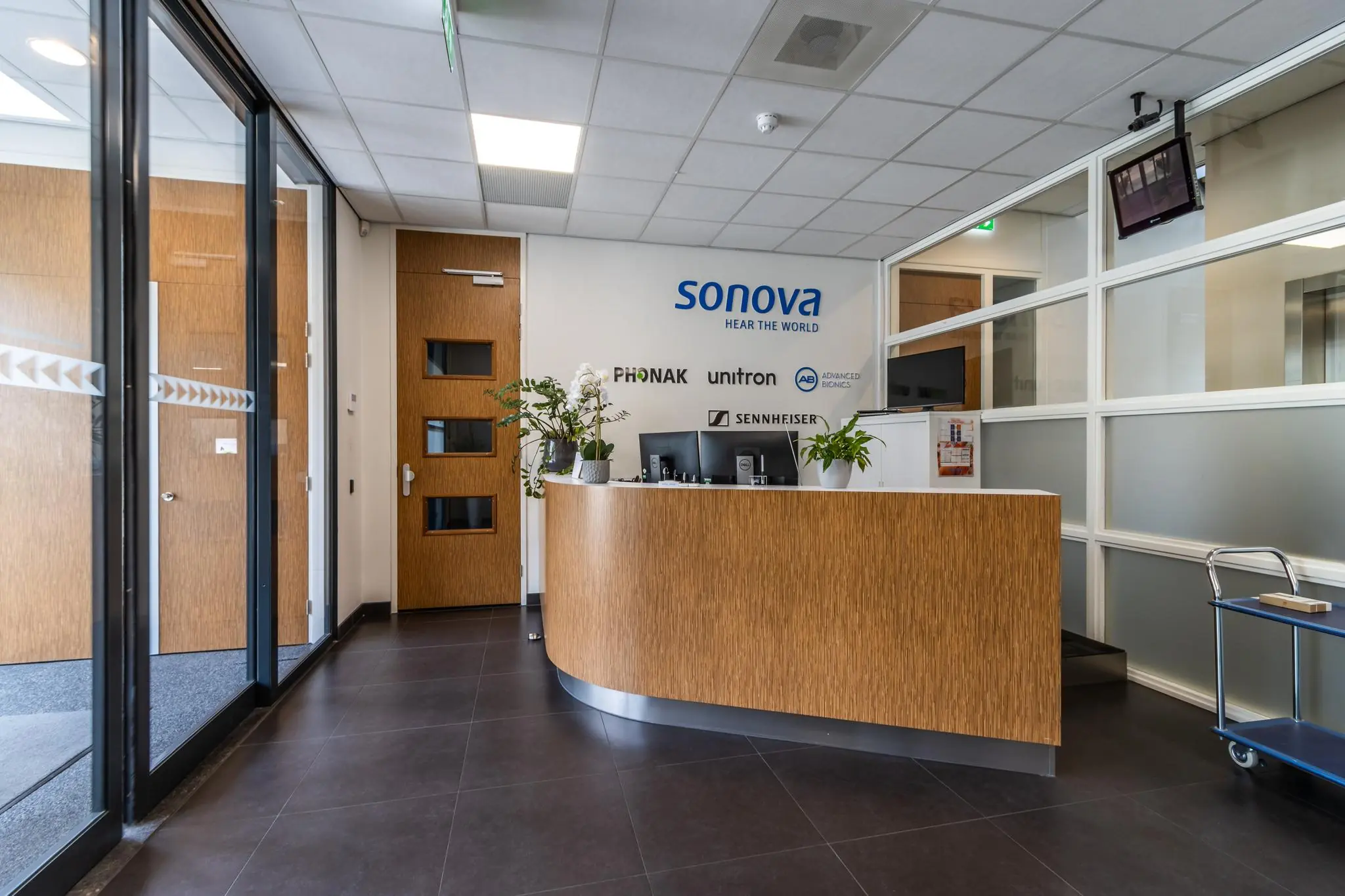 Receptiebalie van het kantoor van Sonova aan de Laanakkerweg, met logo’s van aangesloten merken op de muur.