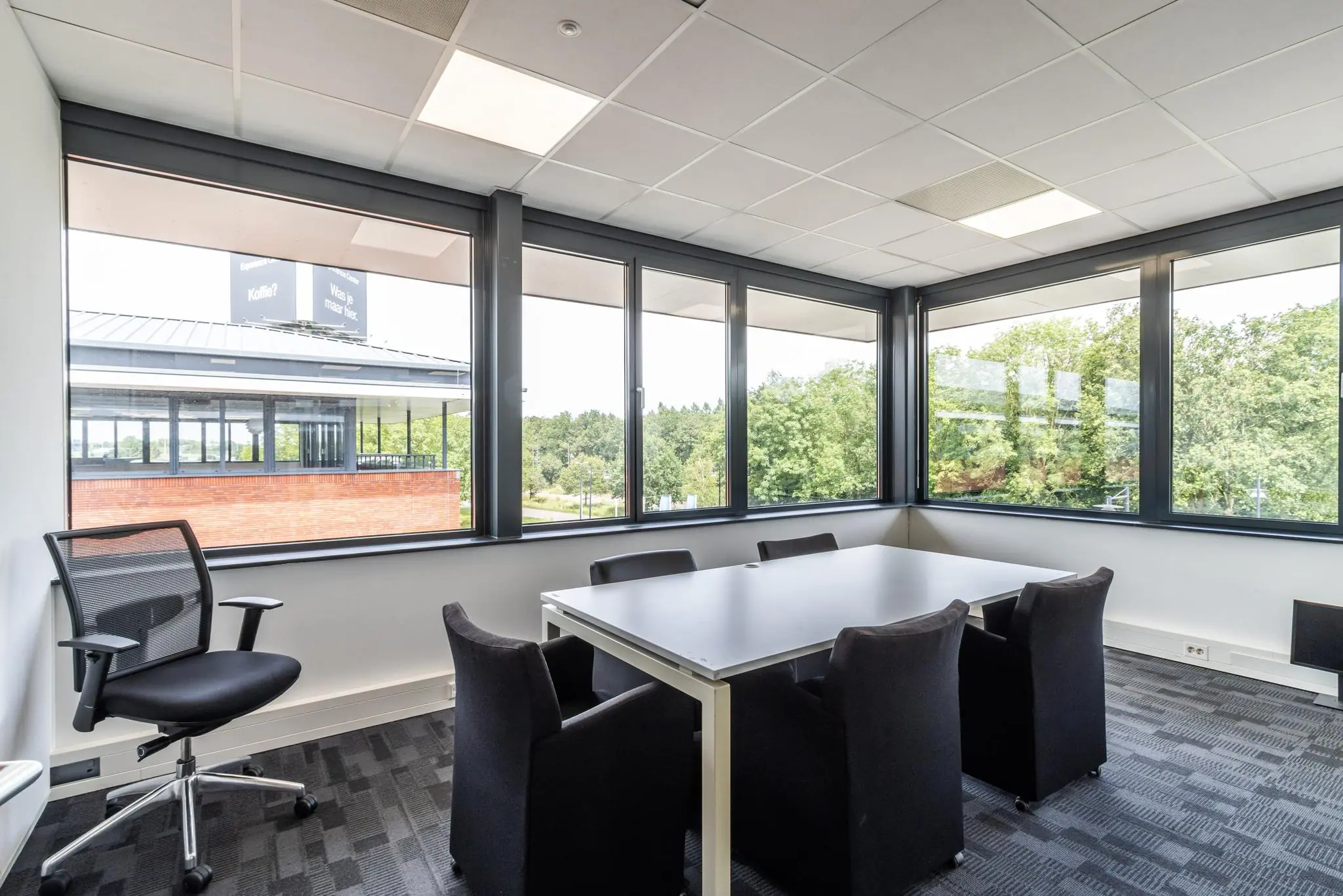 Moderne vergaderruimte aan de Laanakkerweg met grote ramen en uitzicht op groen.