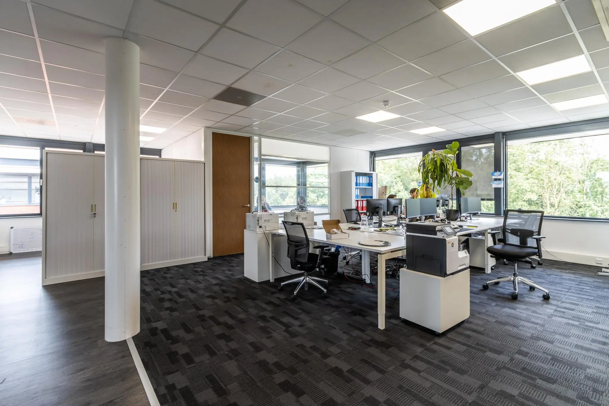 Modern ingericht kantoor op Laanakkerweg met werkplekken, bureaustoelen, planten en grote ramen.
