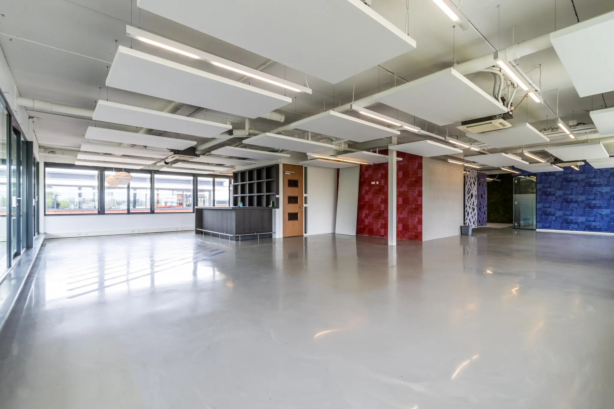 Ruime en moderne kantoorruimte aan de Laanakkerweg met kleurrijke wandaccenten, grote ramen en een strakke gietvloer.