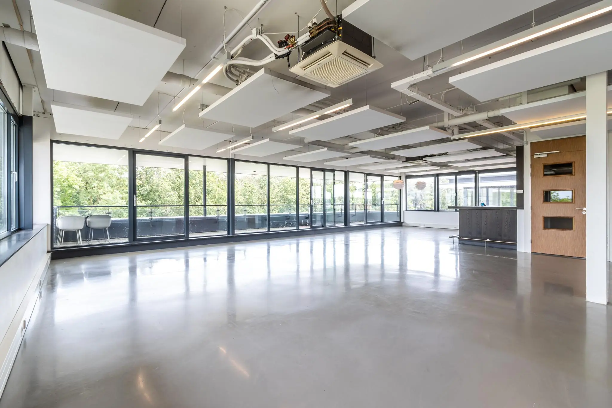 Lichte, moderne kantoorruimte aan de Laanakkerweg met grote ramen en een gladde betonnen vloer.