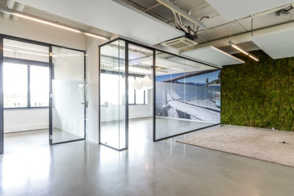 Modern kantoorinterieur aan de Laanakkerweg met glazen vergaderruimtes, moswand en natuurprint op glazen wand.
