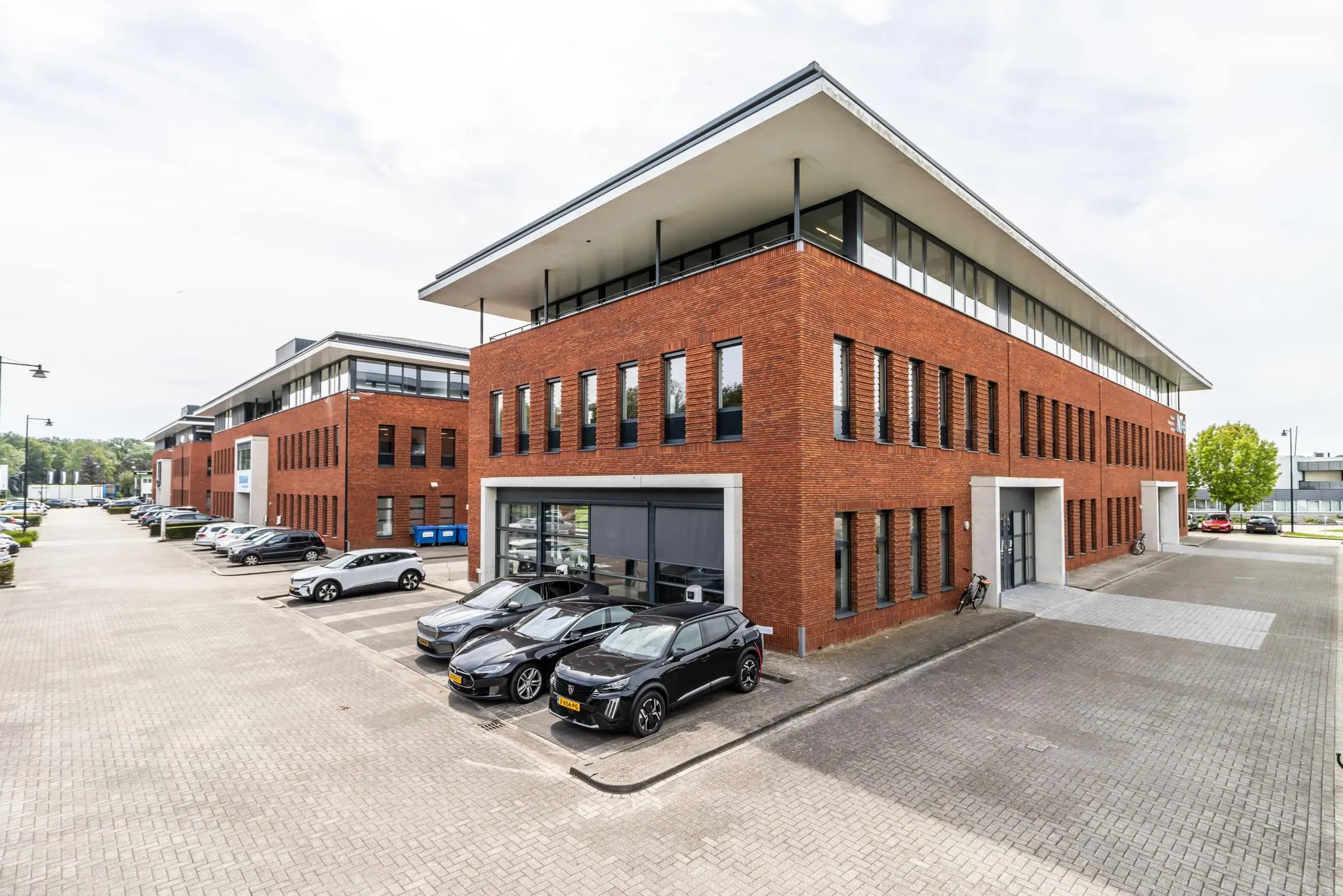 Modern kantoorgebouw aan de Laanakkerweg met parkeerplaatsen en geparkeerde auto's op een bedrijventerrein.