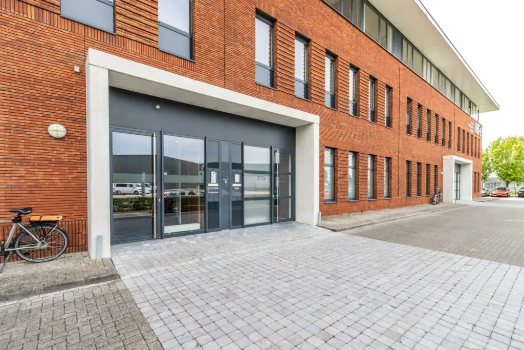 Voorgevel van een modern kantoorpand aan de Laanakkerweg met rood bakstenen gevel en fietsen bij de entree.