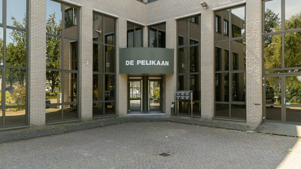 Ingang van kantoorpand De Pelikaan aan de Ligusterbaan met glazen gevel en brievenbussen.