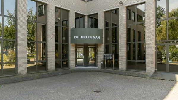 Ingang van kantoorpand De Pelikaan aan de Ligusterbaan met glazen gevel en brievenbussen.