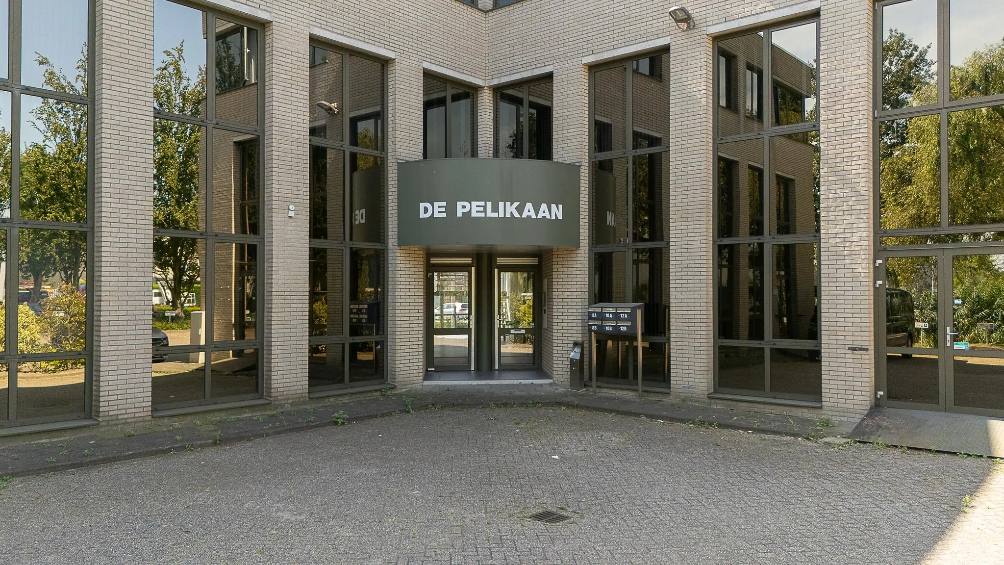 Ingang van kantoorpand De Pelikaan aan de Ligusterbaan met glazen gevel en brievenbussen.