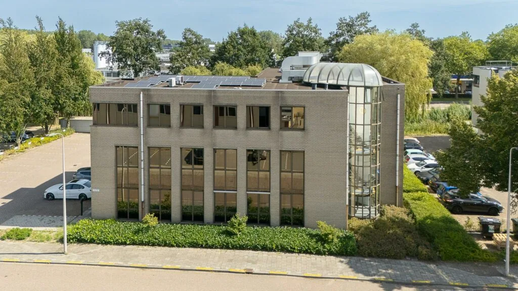Kantoorpand aan de Ligusterbaan met glazen trappenhuis en omliggende parkeerplaatsen.