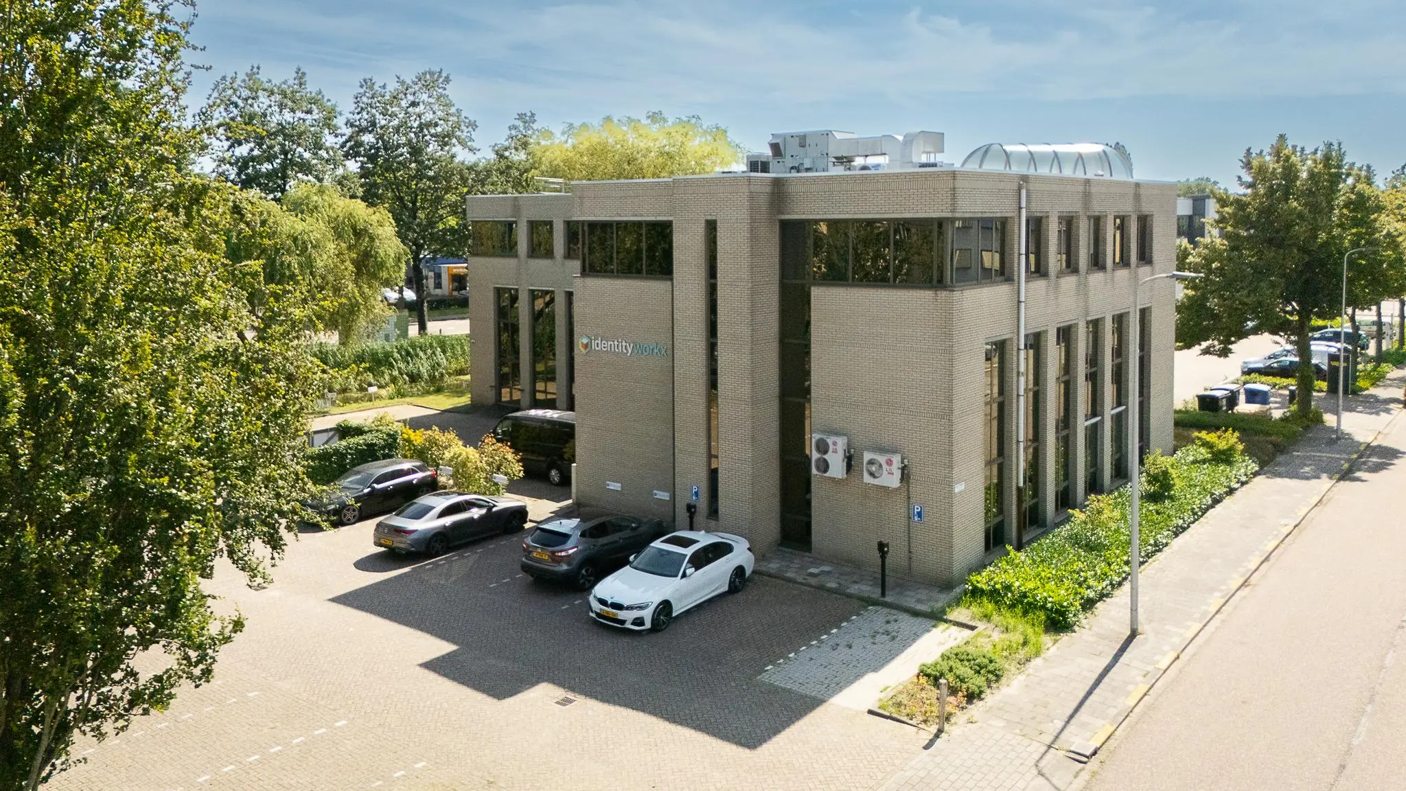 Kantoorpand van Identity Workx aan de Ligusterbaan met geparkeerde auto's op de voorgrond.