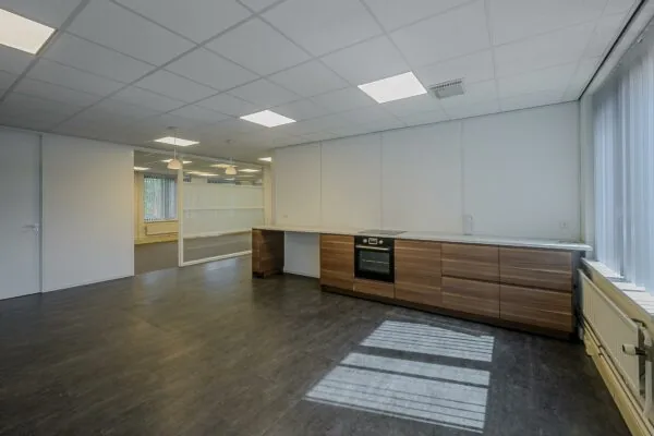 Moderne lege kantoorkeuken met houten onderkasten, ingebouwde oven en glazen scheidingswand aan de Ligusterbaan.