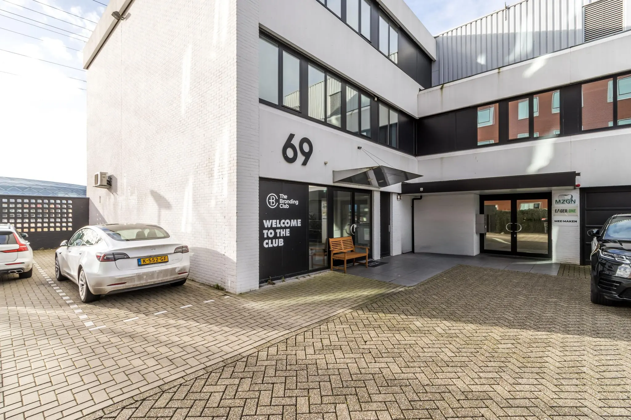 Vooraanzicht van een modern kantoorgebouw aan de Savannahweg 69 met bedrijfsentrees van The Branding Club en MZGN.