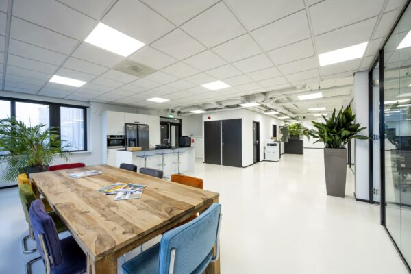 Moderne kantoorruimte aan de Savannahweg met kleurrijke stoelen, houten vergadertafel en open keuken.