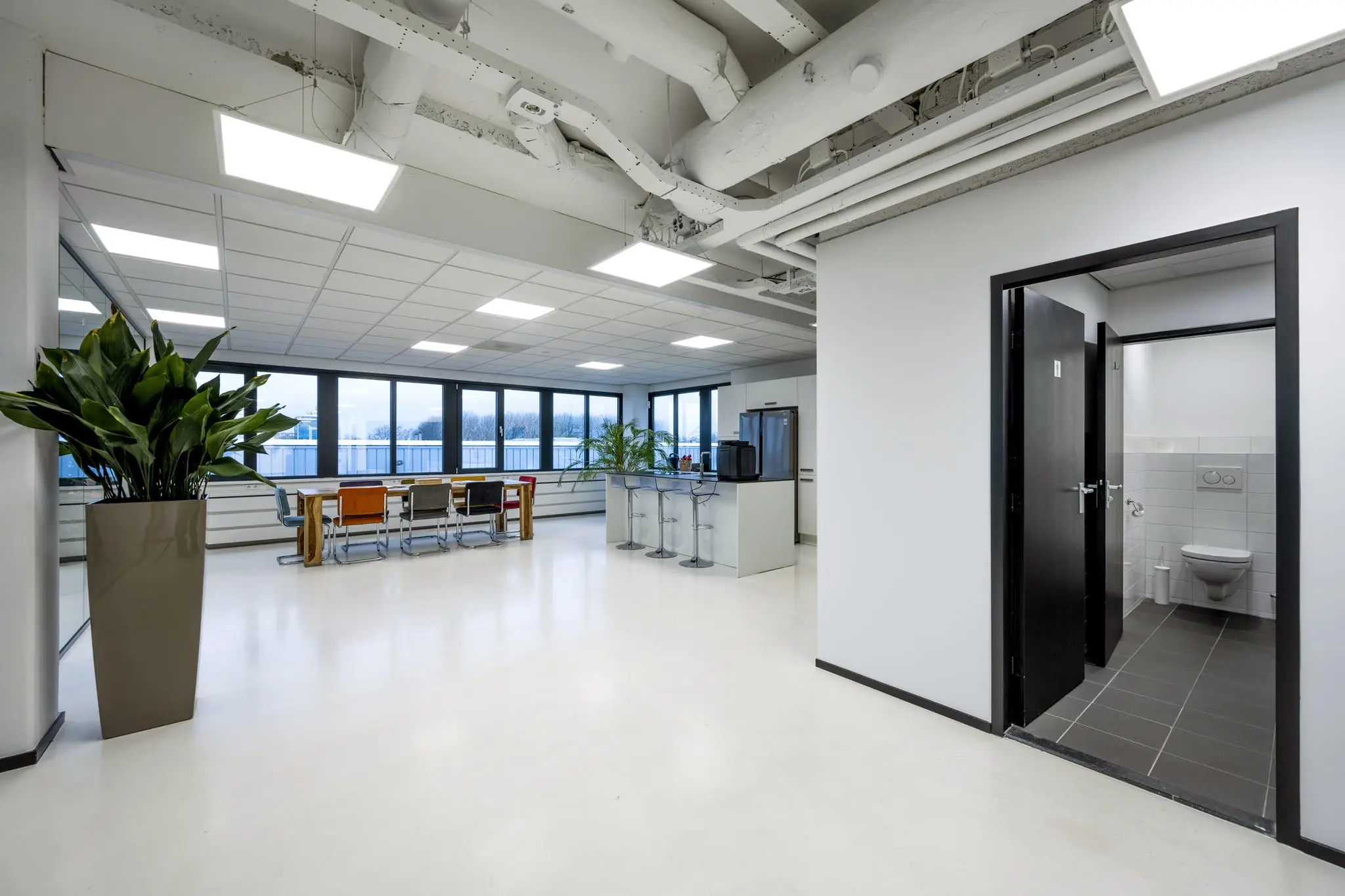 Moderne kantoorruimte aan de Savannahweg met open keuken, vergadertafel en toiletruimte.