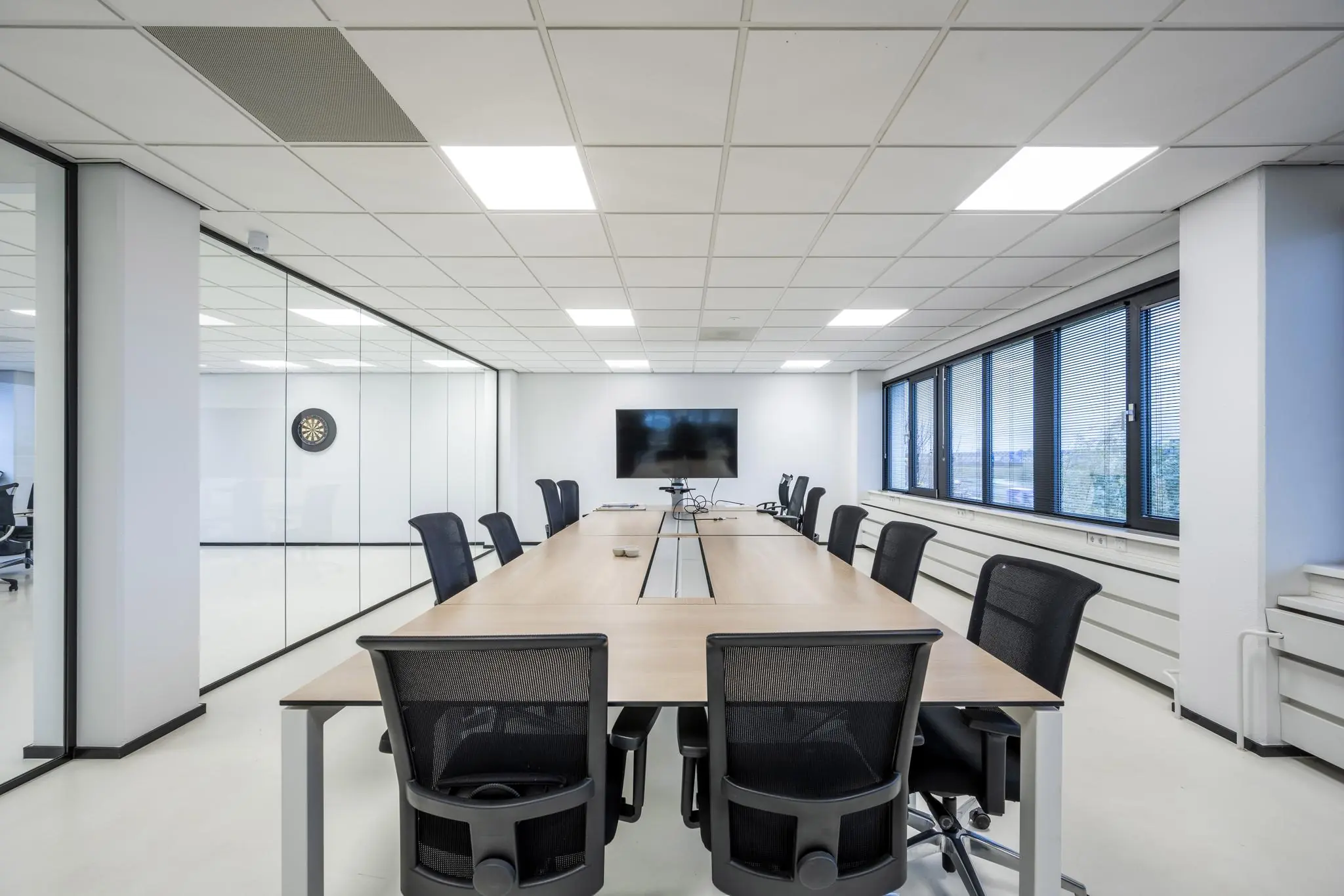 Moderne vergaderruimte aan de Savannahweg met lange tafel, kantoorstoelen, groot scherm en glazen wanden.