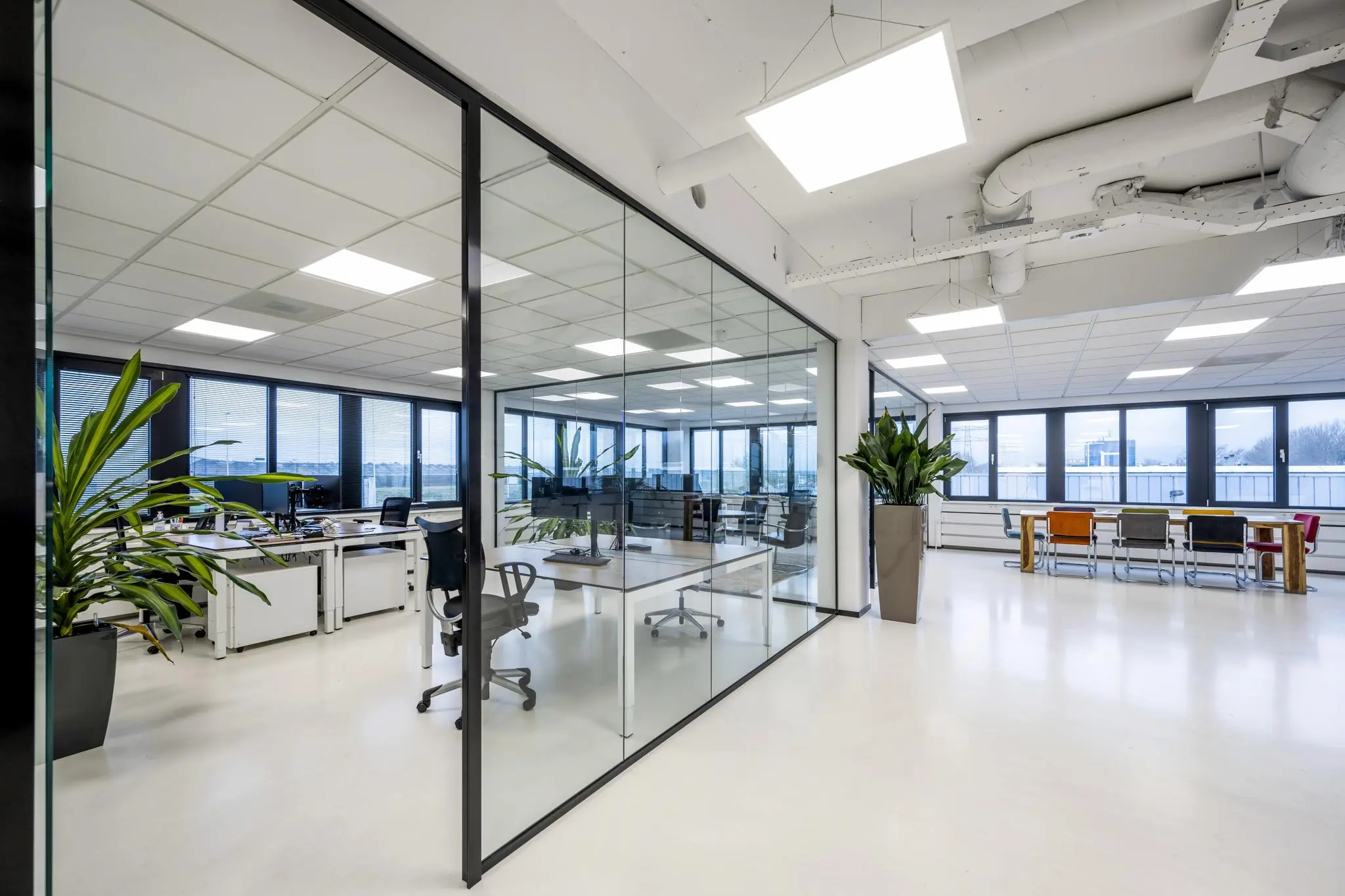 Modern kantoorinterieur aan de Savannahweg met glazen vergaderruimte, bureaus en kleurrijke stoelen in een open ruimte.