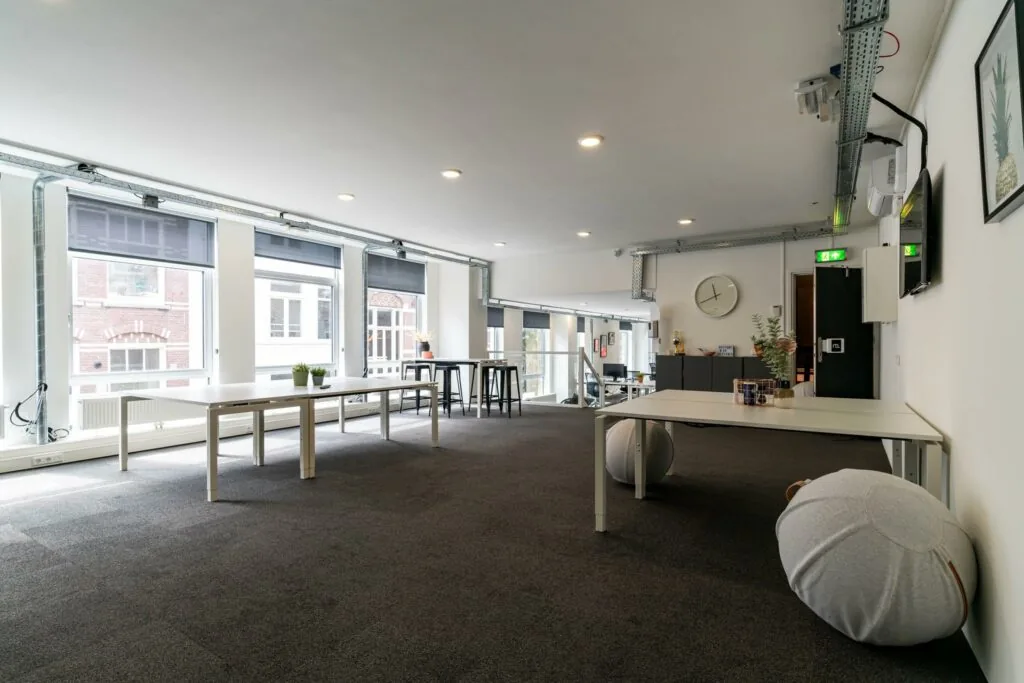 Moderne, lichte kantoorruimte met grote ramen, minimalistische meubels en een open indeling.