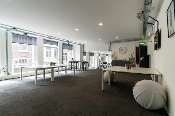 Moderne, lichte kantoorruimte met grote ramen, minimalistische meubels en een open indeling.