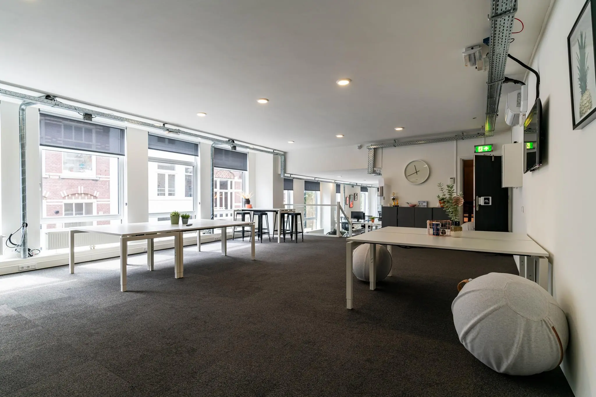 Moderne, lichte kantoorruimte met grote ramen, minimalistische meubels en een open indeling.