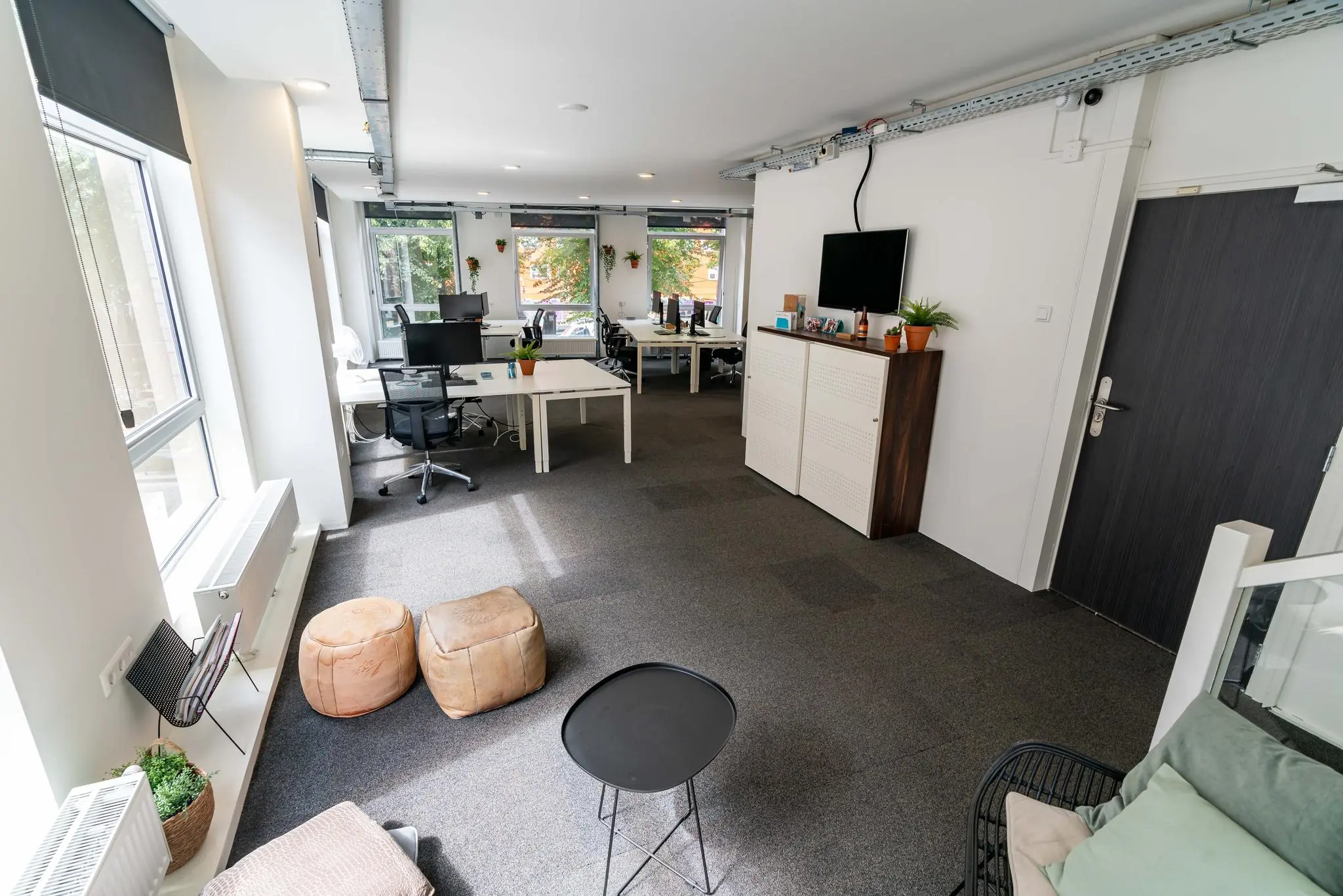 Moderne en lichte kantooruimte met werkplekken, zitgedeelte en planten aan het raam.