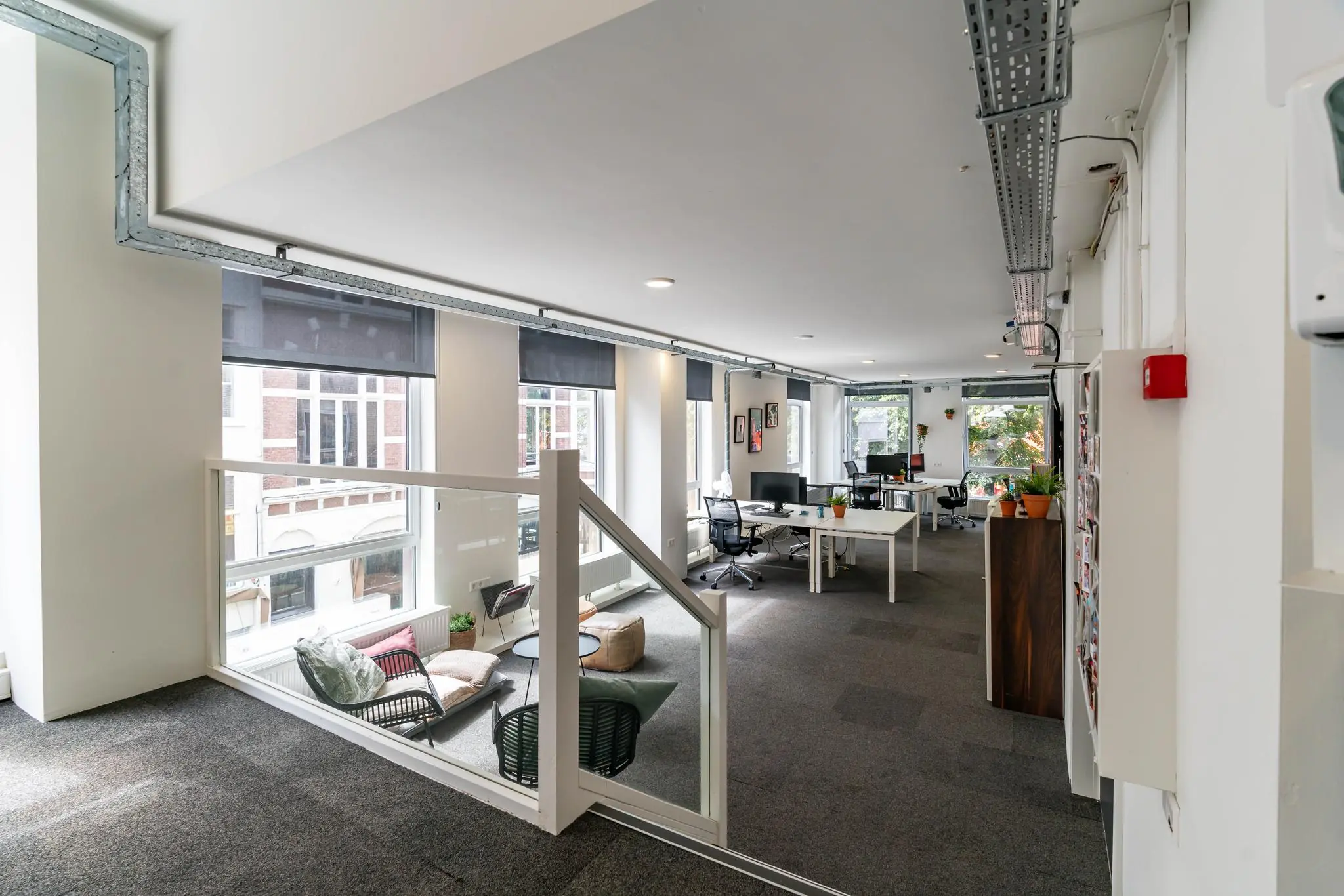 Modern en licht kantoorinterieur aan het Plein met open werkplekken en een gezellige zithoek bij het raam.