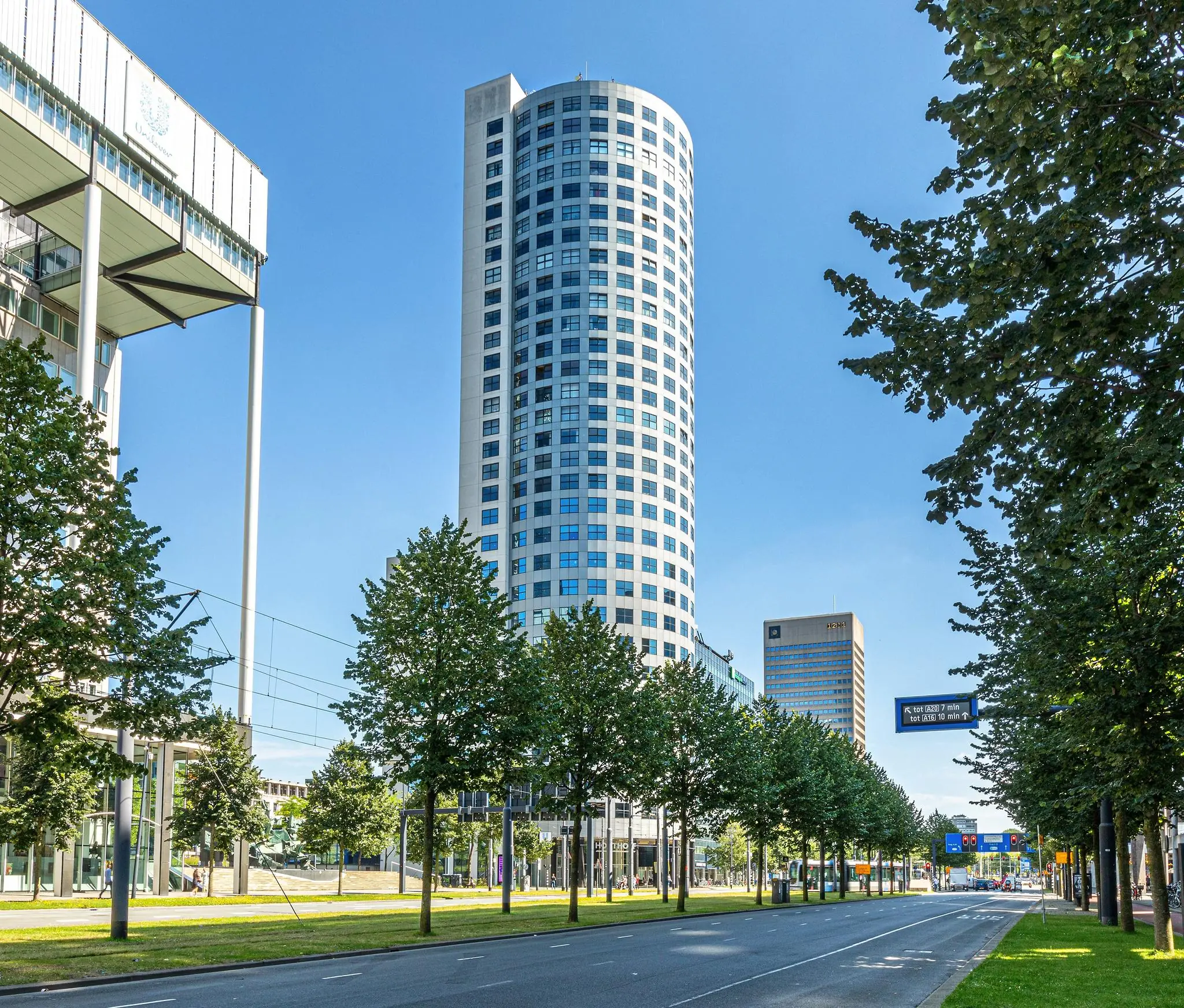 Hoog kantoorgebouw aan de Weena in Rotterdam, omringd door bomen en een brede stadsweg.