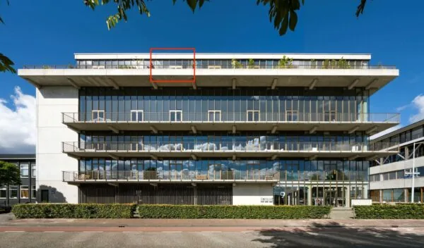 Voorgevel van het moderne kantoorgebouw aan de Danzigerkade 9 in Amsterdam met gemarkeerde bovenverdieping.