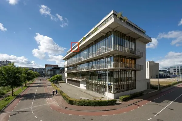 Modern kantoorgebouw aan de Danzigerkade in Amsterdam met grote glazen gevels en terrassen, gezien vanaf de straat.