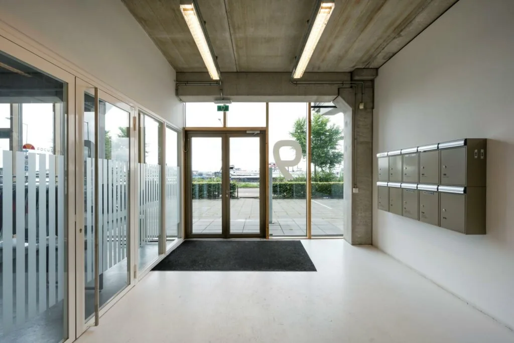 Ingang van een modern bedrijfsverzamelgebouw aan de Danzigerkade met postbussen en glazen deuren.