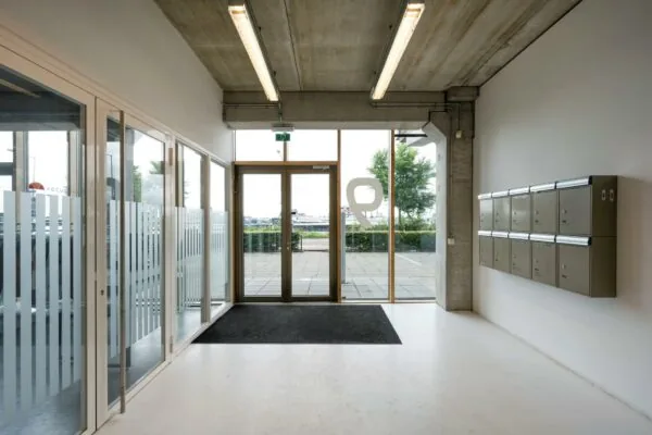 Ingang van een modern bedrijfsverzamelgebouw aan de Danzigerkade met postbussen en glazen deuren.