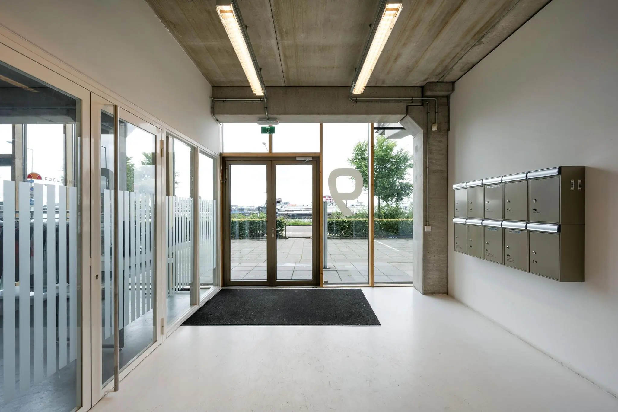 Ingang van een modern bedrijfsverzamelgebouw aan de Danzigerkade met postbussen en glazen deuren.