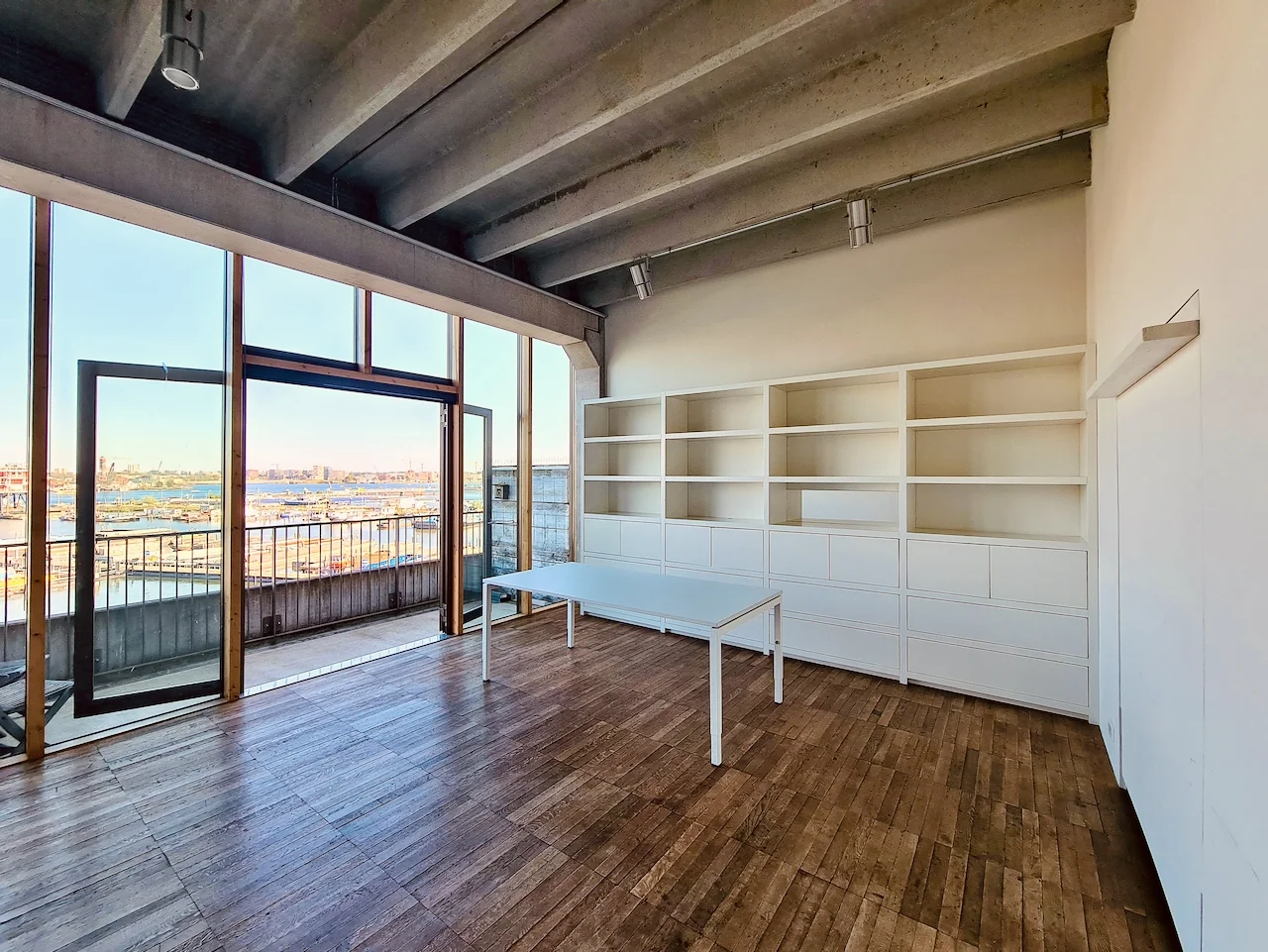 Lichte, moderne ruimte aan de Danzigerkade met houten vloer, witte kastenwand en uitzicht op het havengebied.