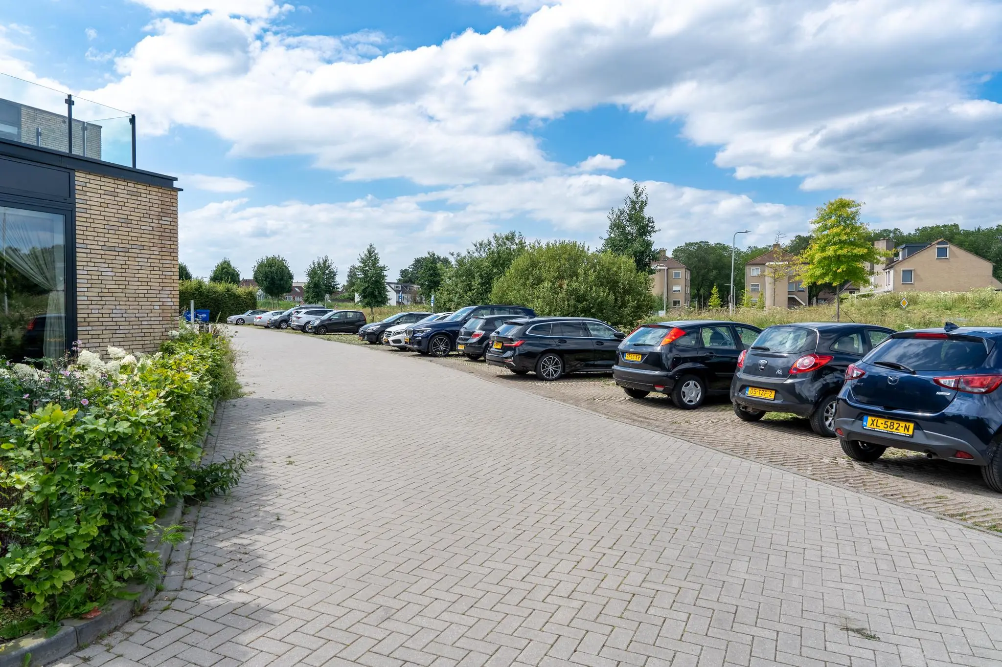 Parkeerplaats in een woonwijk aan de Handboog met geparkeerde auto's en een blauwe lucht.