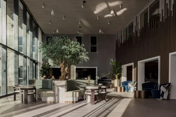 Moderne, lichte lounge met grote raampartijen, een centrale boom en stijlvolle zitplekken in het Diemerhof gebouw.