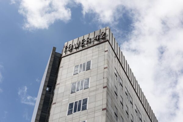 Hoekaanzicht van de bovenste verdiepingen van kantoorgebouw Tower 42 in Diemen tegen een deels bewolkte lucht.