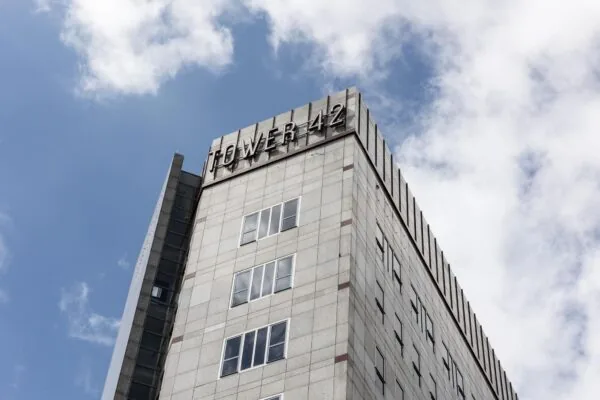 Hoekaanzicht van de bovenste verdiepingen van kantoorgebouw Tower 42 in Diemen tegen een deels bewolkte lucht.