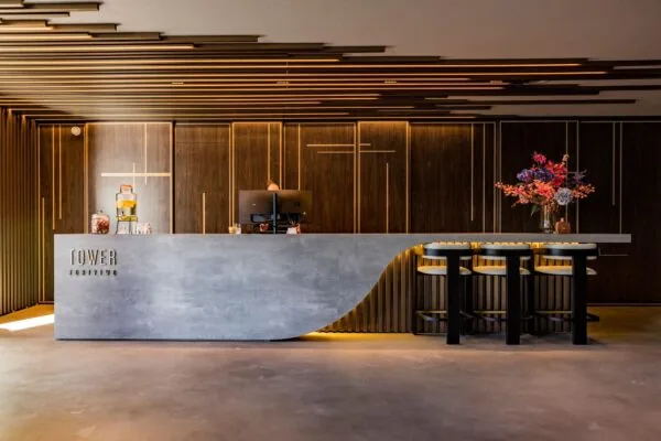 Moderne receptiebalie van TOWER FortyTwo met strakke lijnen, sfeervolle verlichting en een vaas met kleurrijke bloemen.