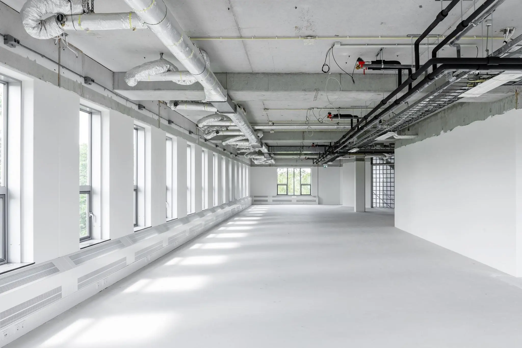 Lichte, lege kantoorruimte in Diemerhof met zichtbare leidingen en grote ramen.
