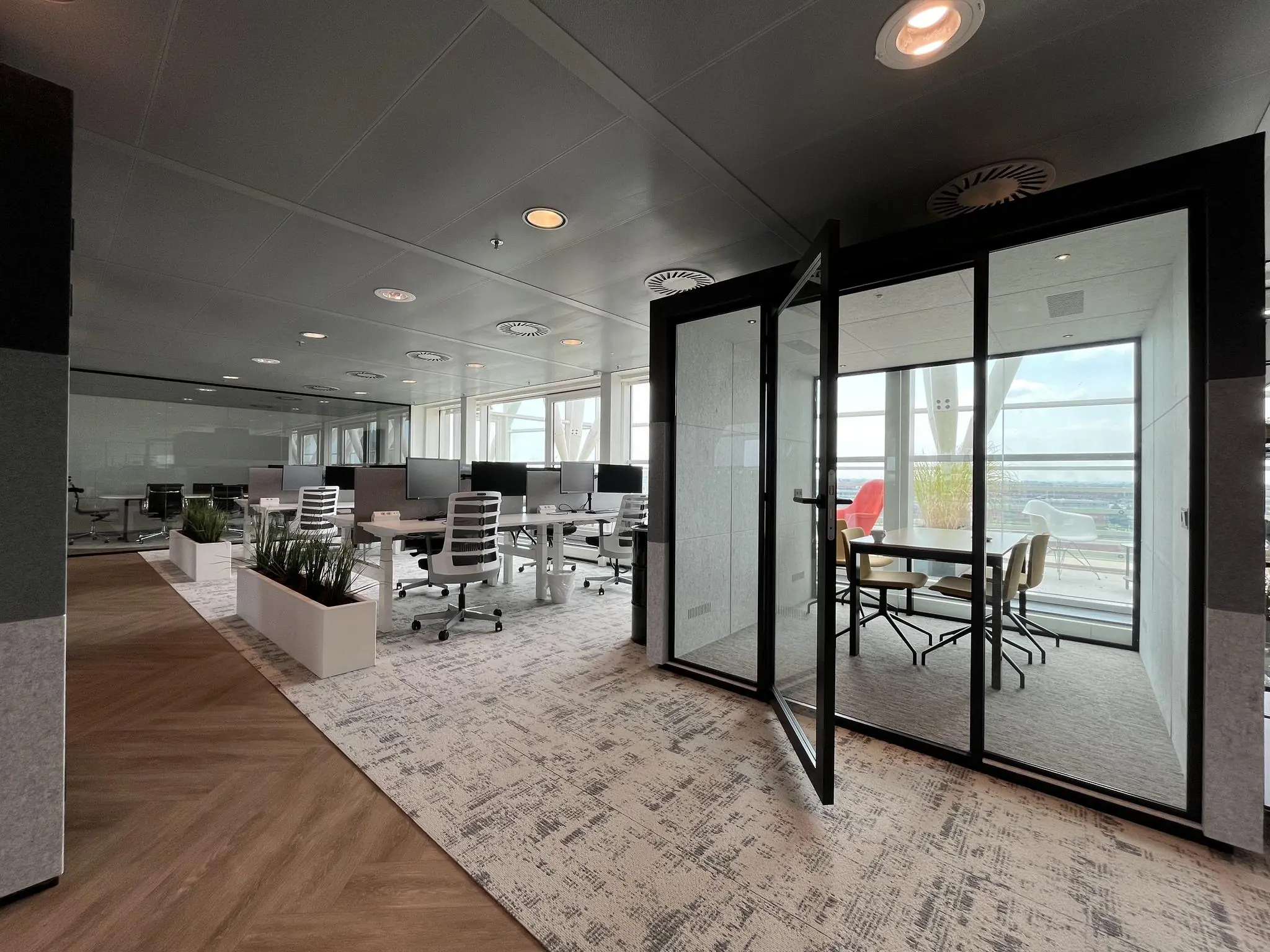 Modern kantoorinterieur aan de Reactorweg met open werkplekken en een glazen vergaderruimte met uitzicht.