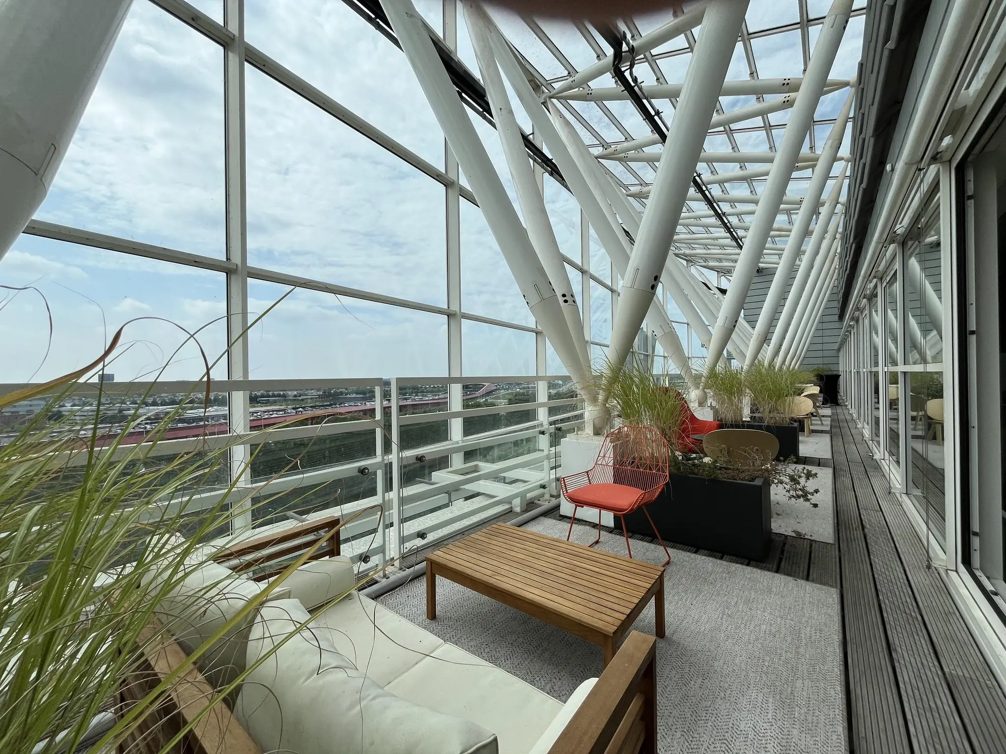 Overdekt dakterras met moderne zitmeubels en uitzicht op bedrijventerrein aan de Reactorweg.