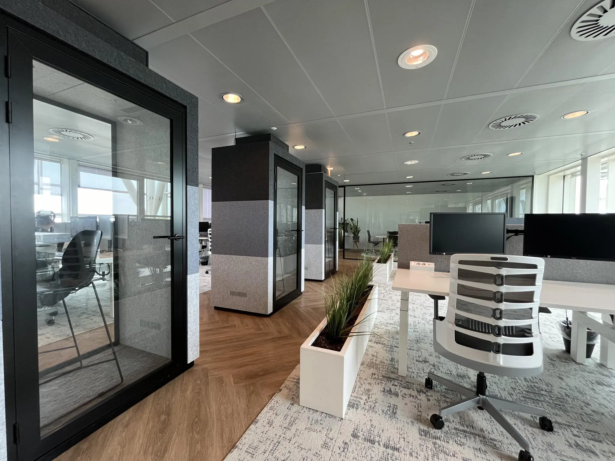 Modern kantoorinterieur aan de Reactorweg met werkplekken, belcellen en plantenbakken.