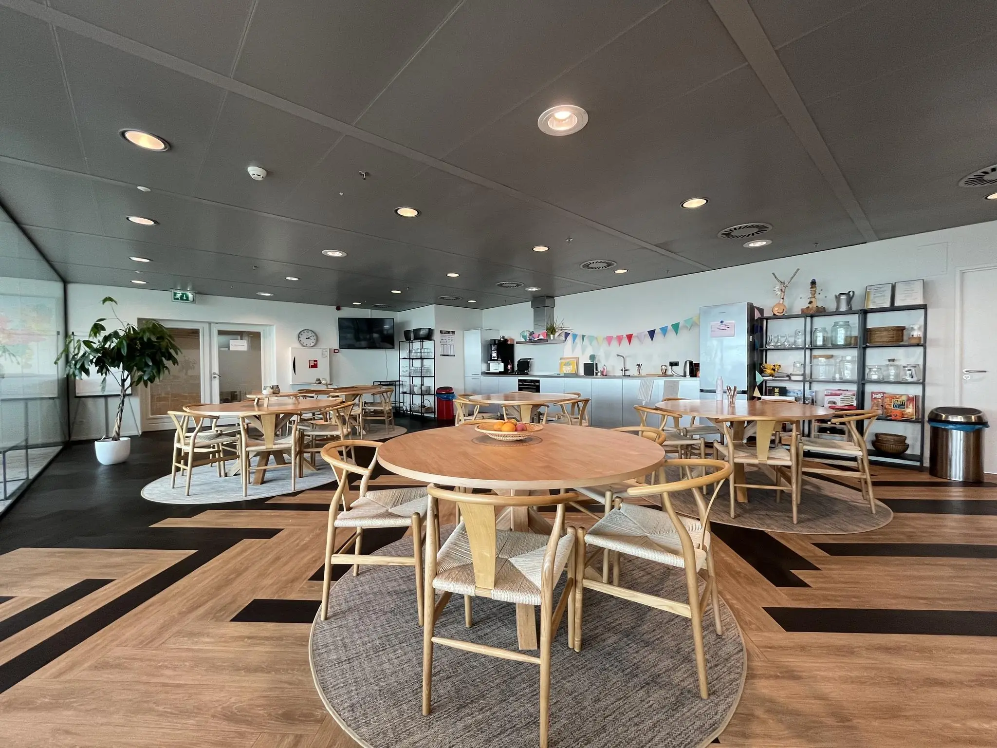 Moderne bedrijfskantine aan de Reactorweg met ronde tafels, open keuken en decoratieve slingers.