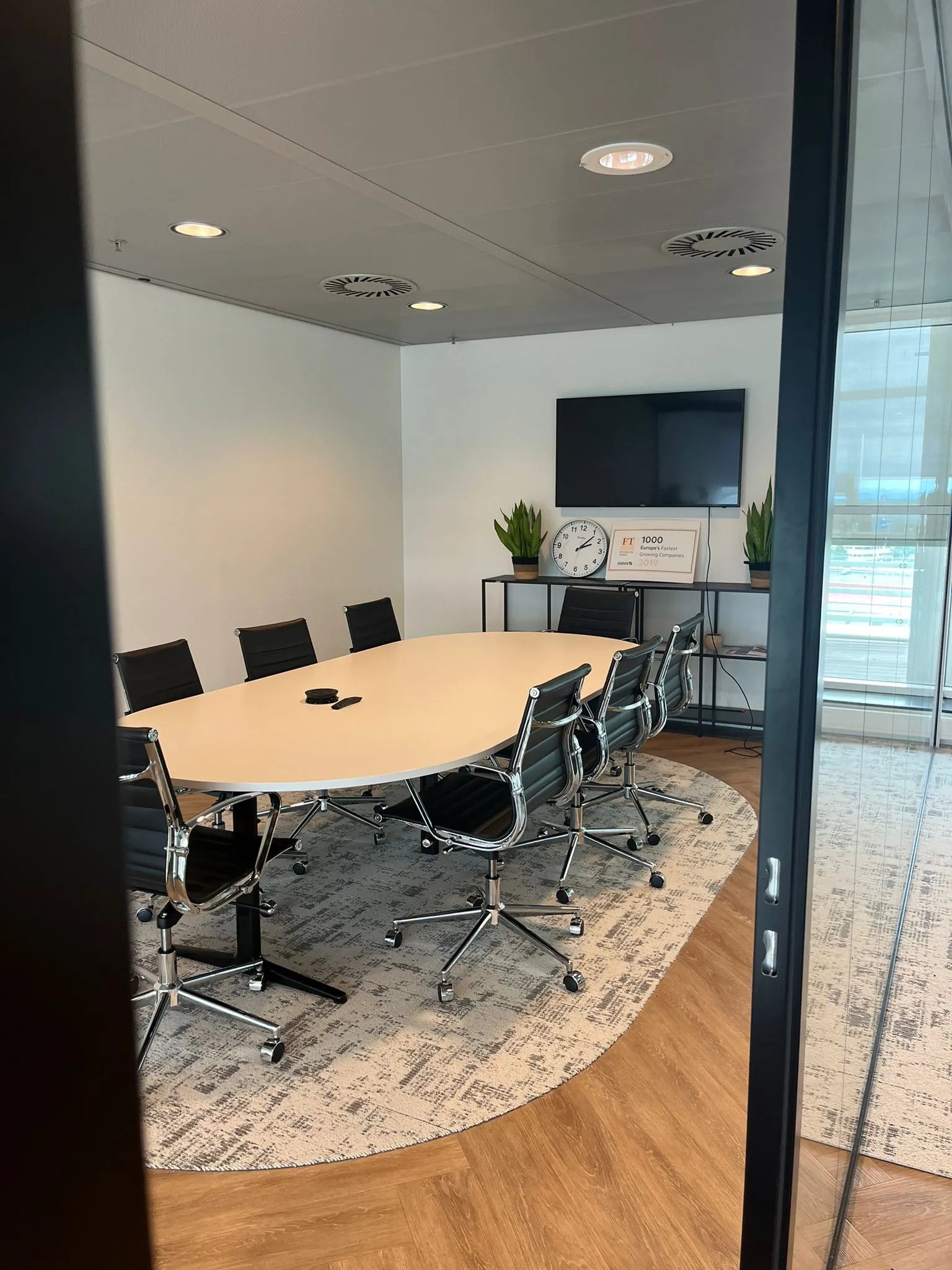 Vergaderruimte aan de Reactorweg met ovale tafel, zwarte stoelen, tv-scherm en wanddecoratie.