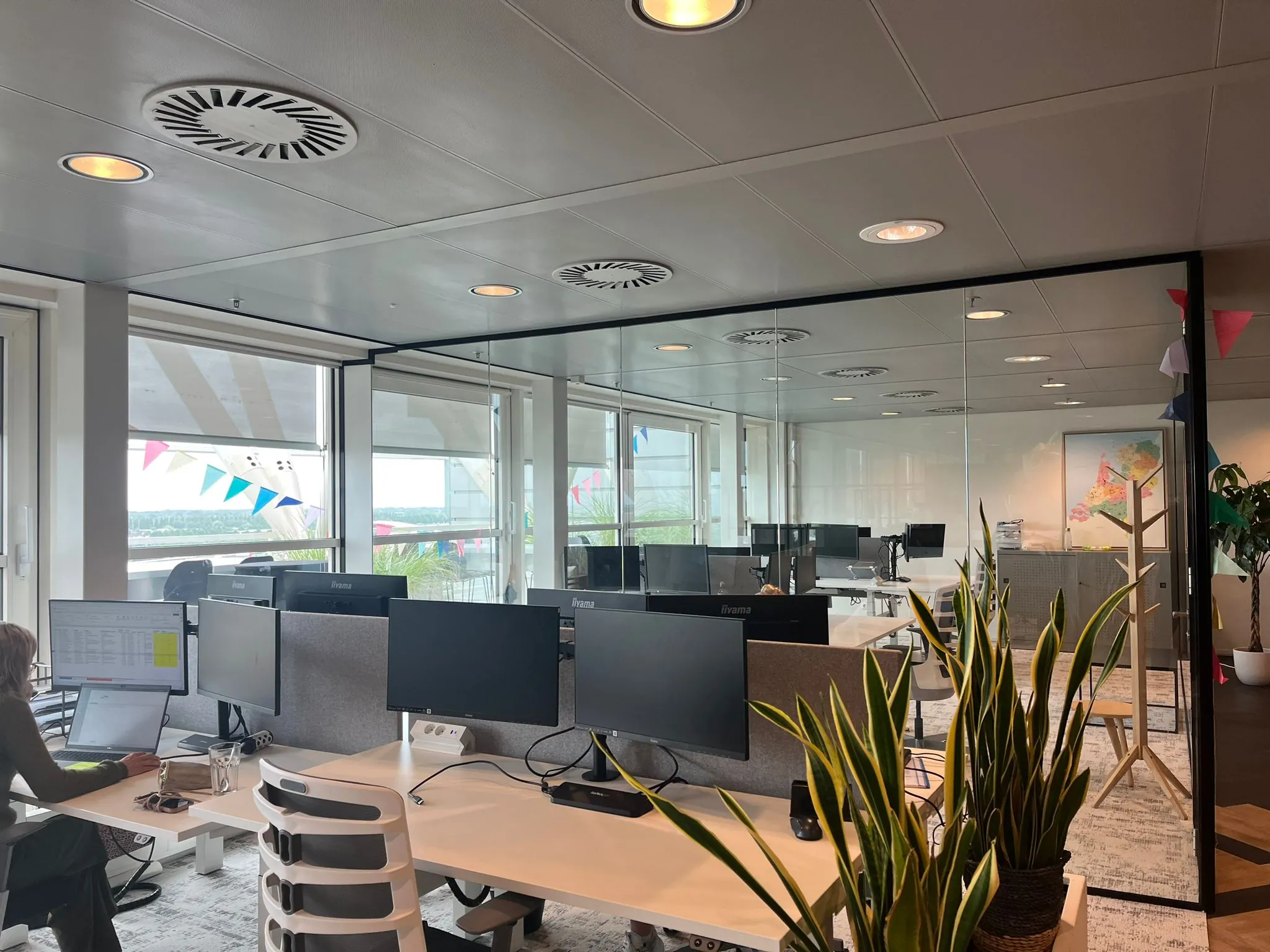 Modern kantoor aan de Reactorweg met werkplekken, glazen wanden, kamerplanten en kleurrijke vlaggetjes.