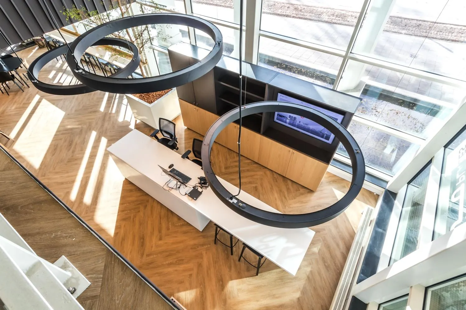 Moderne ontvangstruimte aan de Reactorweg met een strak wit bureau, houten vloer en grote ronde plafondlampen.