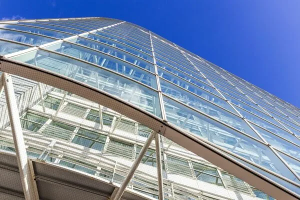 Glazen gevel van een modern kantoorgebouw aan de Reactorweg, gezien van onderaf tegen een heldere blauwe lucht.