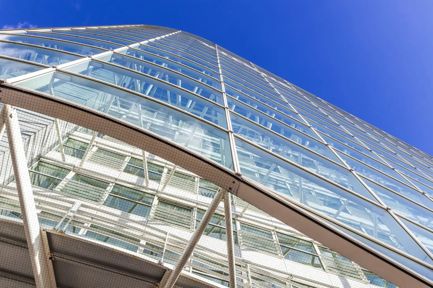 Glazen gevel van een modern kantoorgebouw aan de Reactorweg, gezien van onderaf tegen een heldere blauwe lucht.