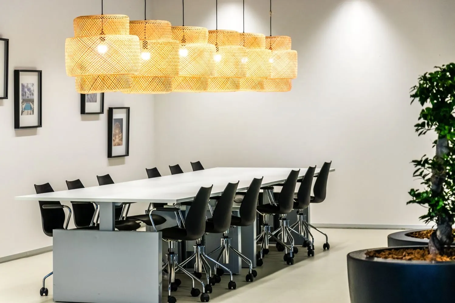 Vergaderruimte met een lange witte tafel, zwarte stoelen, hangende rieten lampen en wanddecoratie op Reactorweg.