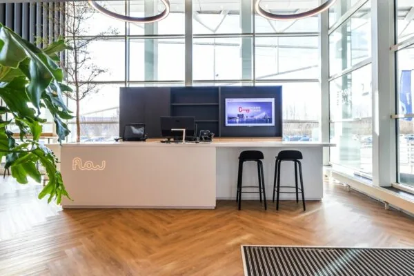 Moderne receptiebalie met het logo "Flow" in een licht en ruim kantoor aan de Reactorweg.