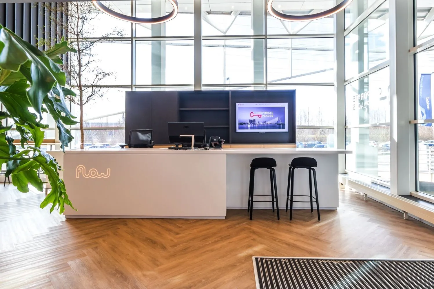 Moderne receptiebalie met het logo "Flow" in een licht en ruim kantoor aan de Reactorweg.